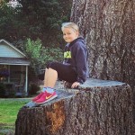 Happy young girl on tree stump at Lake Crescent Lodge.