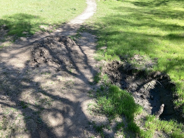 Mountain bikers leave a gaping hole from which they used the dirt to create a bike jump.