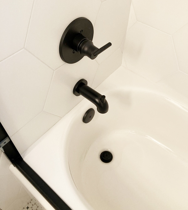 Black Delta mixing valve handle, tub spigot, and drain.