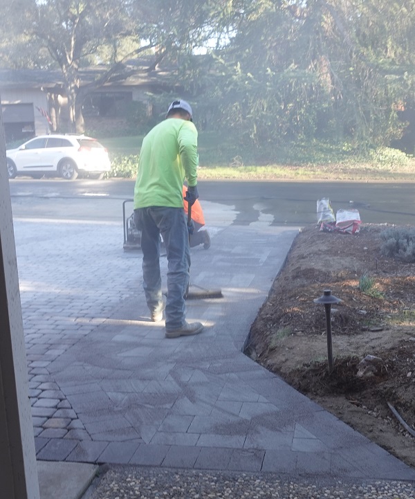 Sweeping polymeric sand into the spaces between the concrete pavers.
