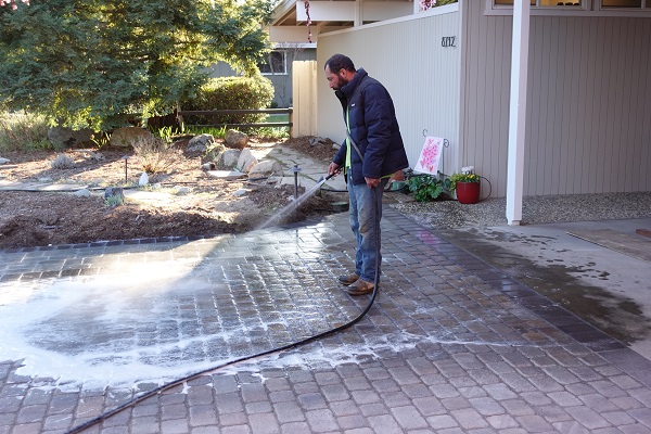 Washing the polymeric sand in to the spaces between the pavers.