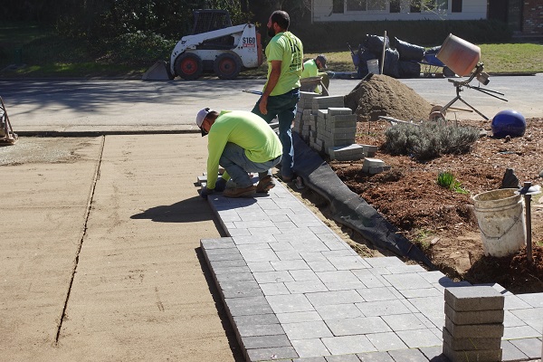 Carefully laying the walkway pavers on top of compacted sand.